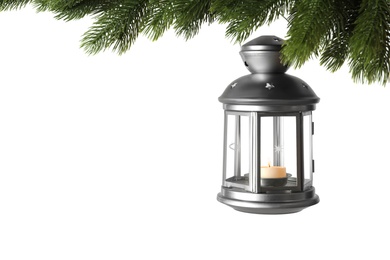 Photo of Christmas lantern with candle hanging on snowy fir tree branch against white background