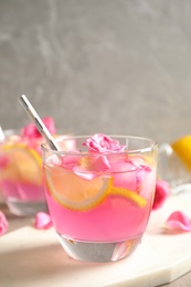 Glass of refreshing drink with lemon and roses on marble table
