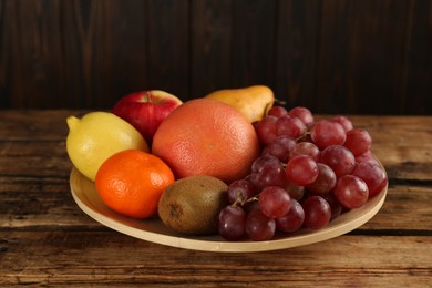 Fresh ripe fruits in bowl on wooden table
