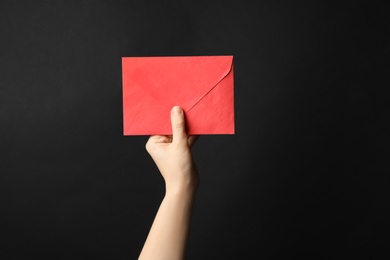 Photo of Woman holding red paper envelope on black background, closeup