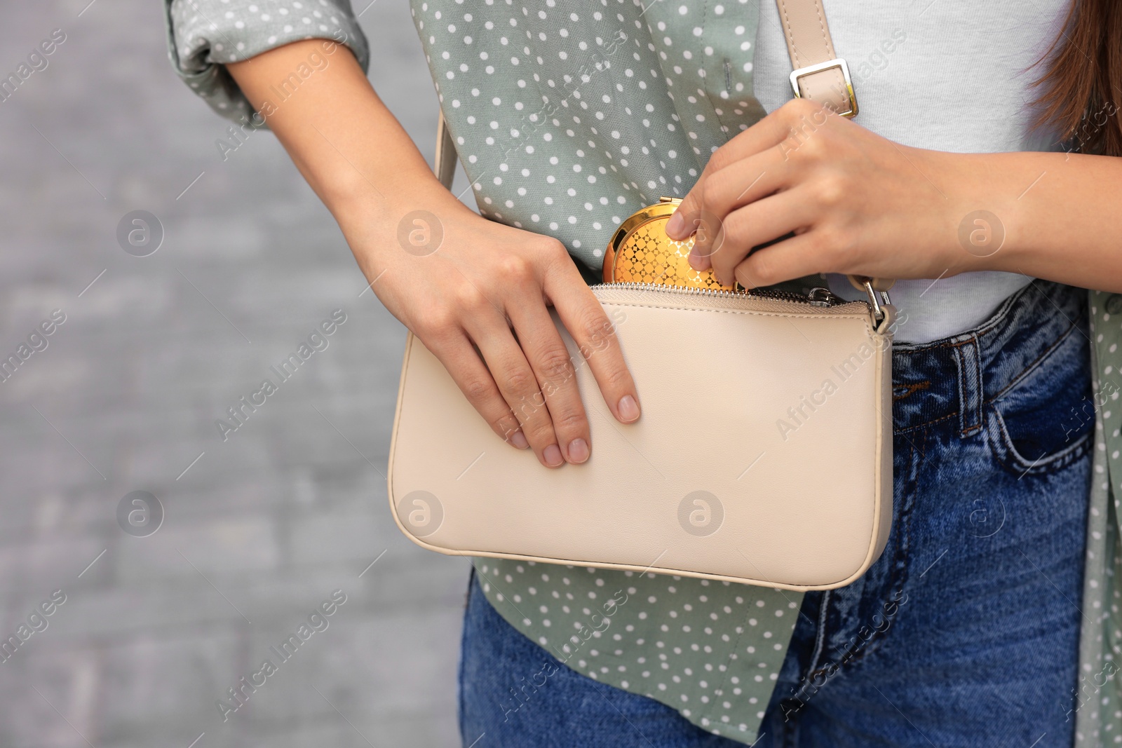 Photo of Woman taking cosmetic pocket mirror from bag outdoors, closeup. Space for text