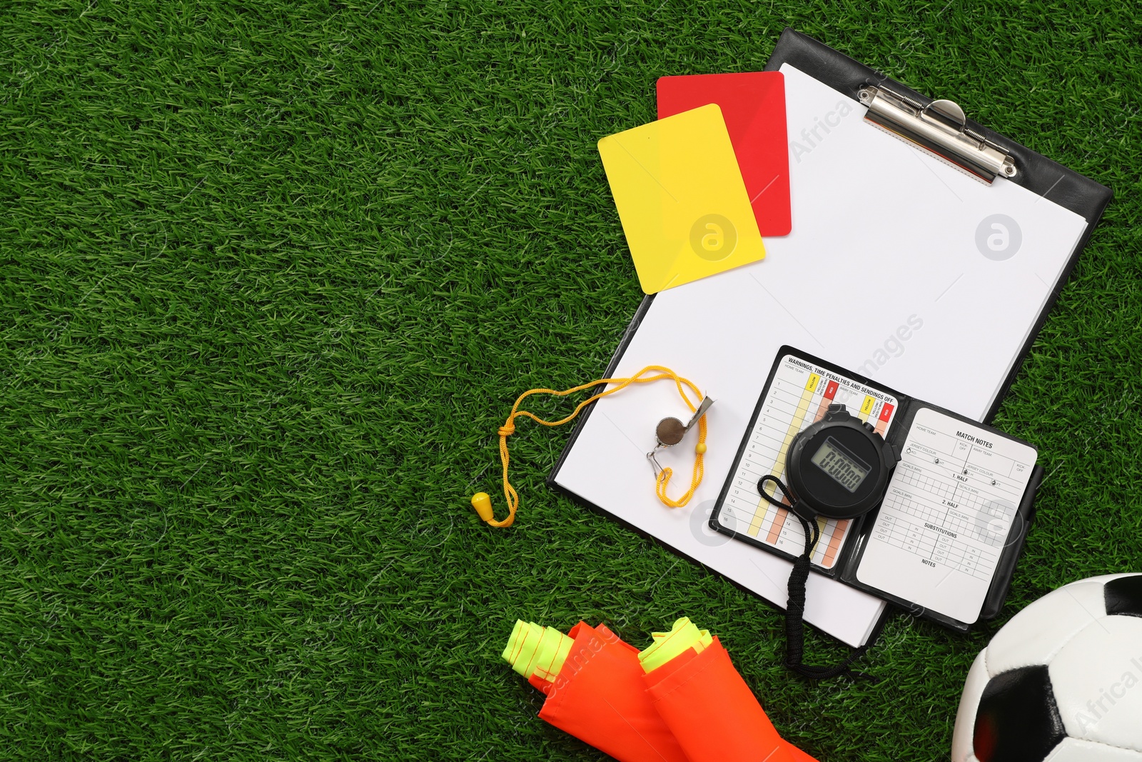 Photo of Soccer ball and different referee equipment on green grass, flat lay. Space for text