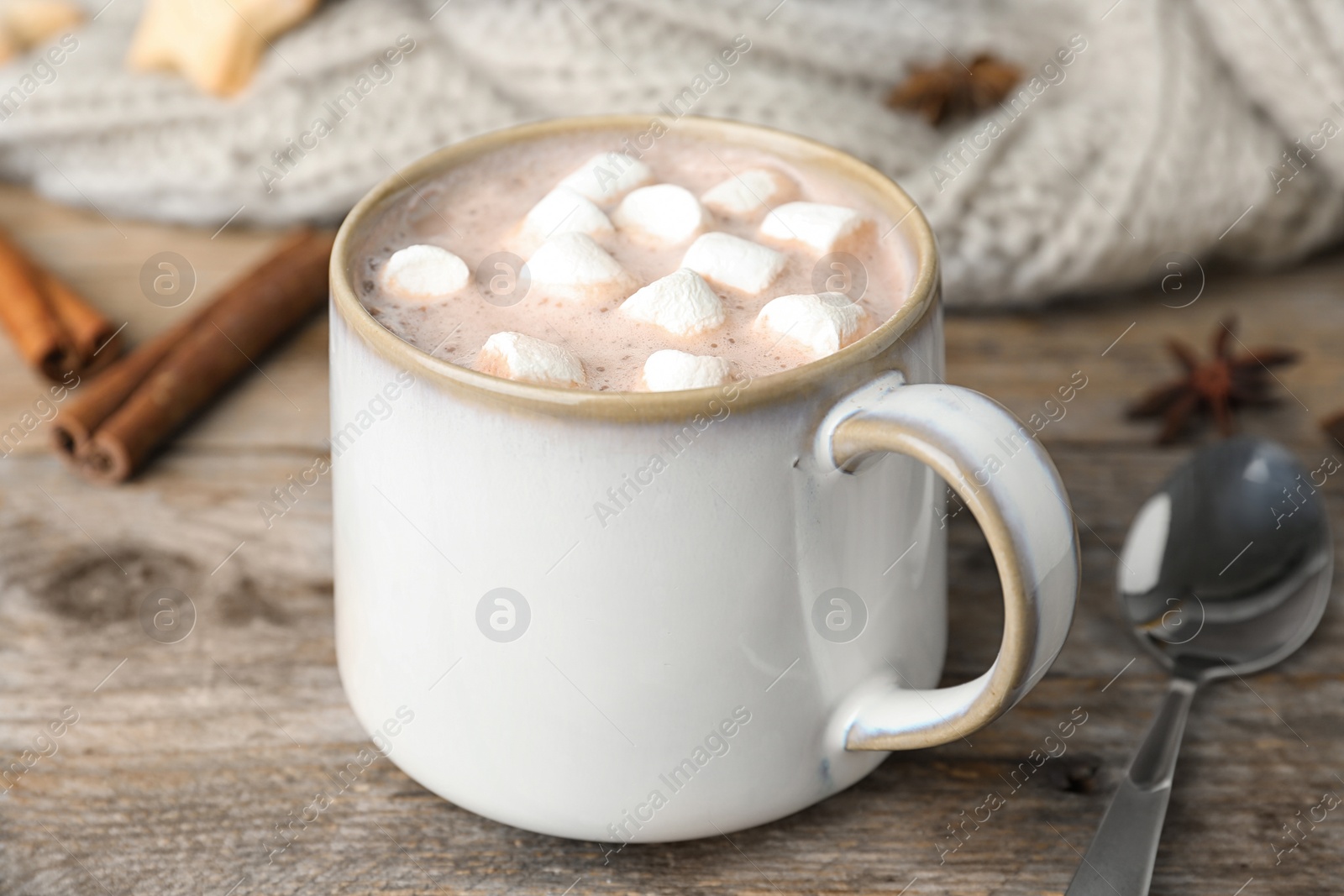 Photo of Delicious hot cocoa drink with marshmallows in cup on wooden table, closeup