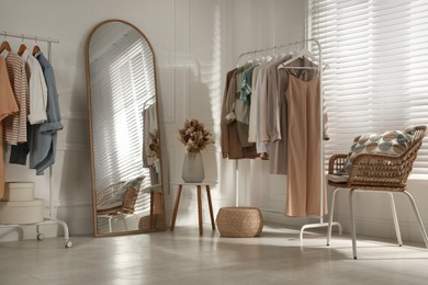 Photo of Modern dressing room interior with stylish clothes and beautiful dry flowers