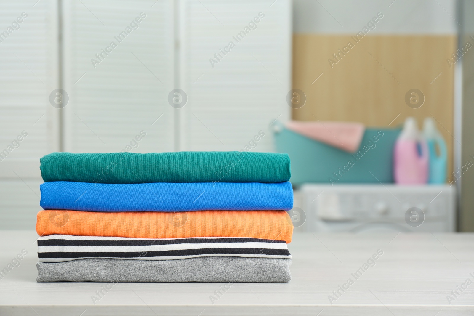 Photo of Fresh laundry on white wooden table in bathroom. Space for text