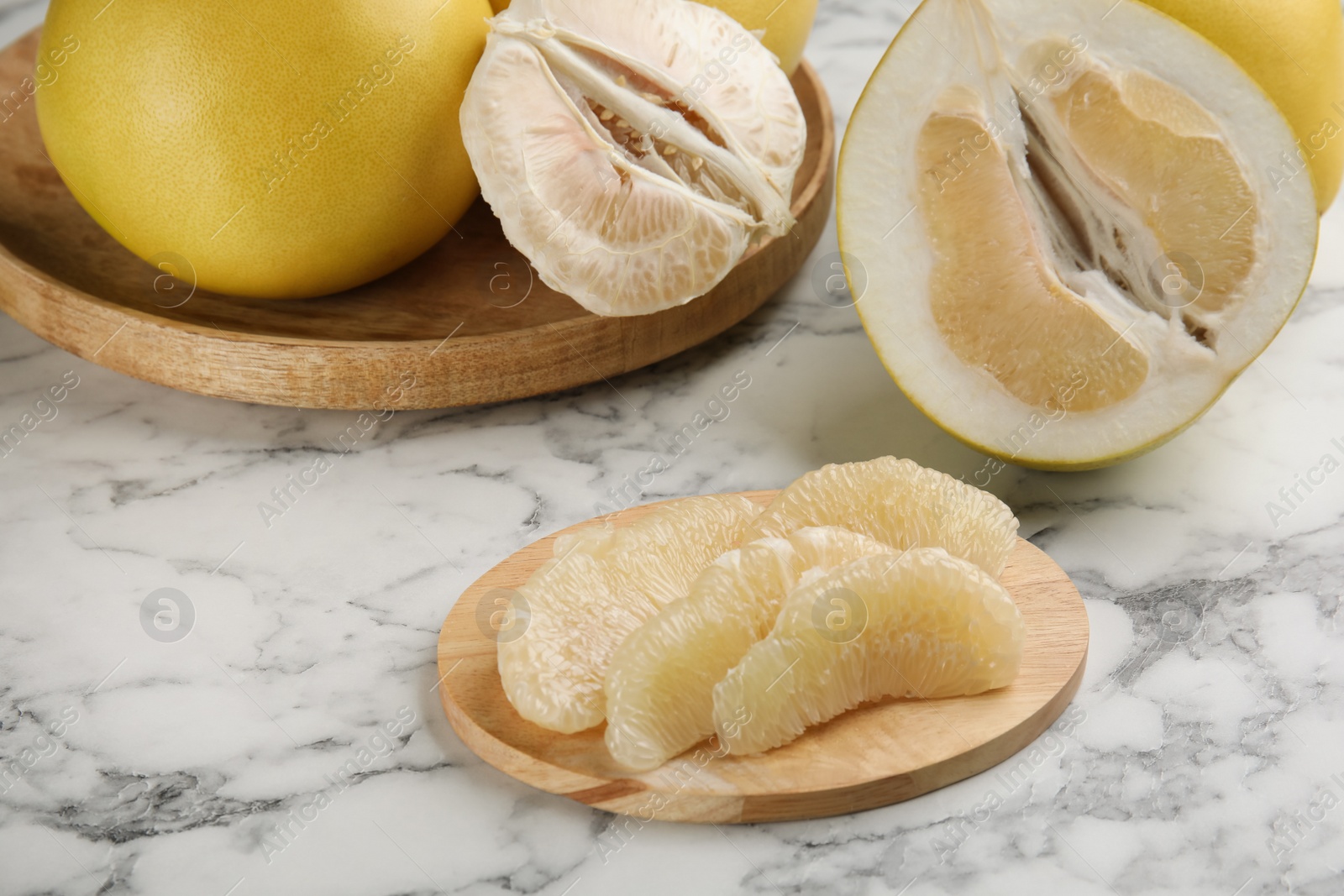 Photo of Peeled yellow pomelo slices on white marble table