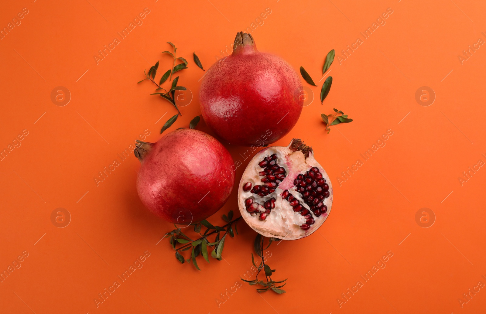 Photo of Flat lay composition with ripe pomegranates on orange background