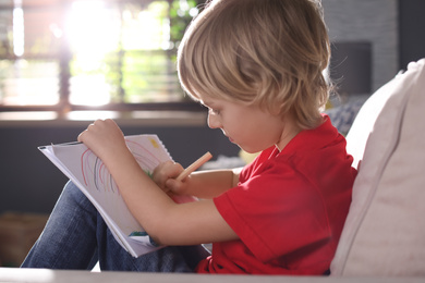 Photo of Little boy drawing on sofa at home. Creative hobby