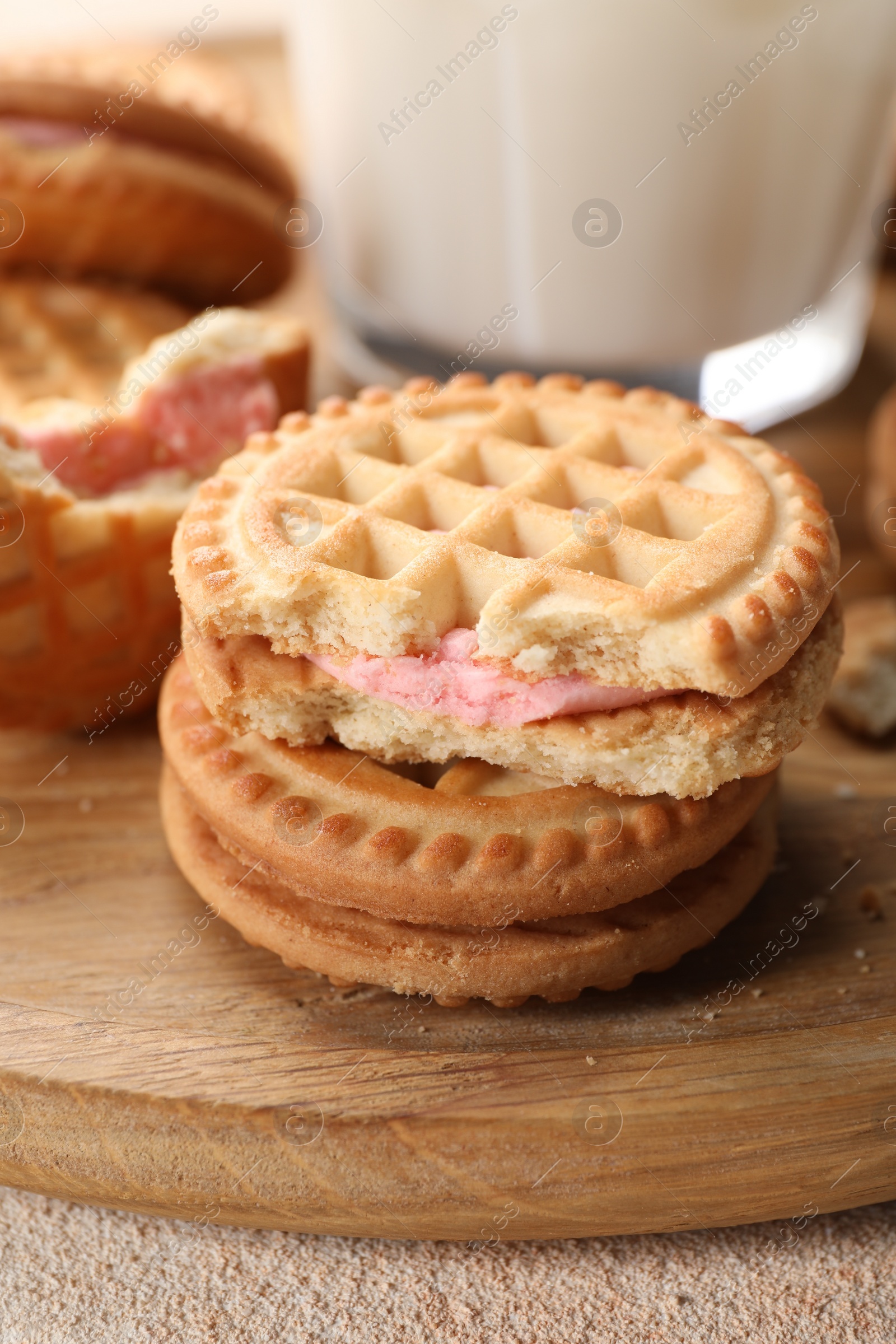 Photo of Tasty sandwich cookies with cream on wooden board, closeup