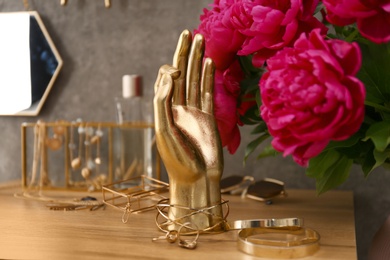 Photo of Composition with gold accessories and flowers on dressing table near grey wall