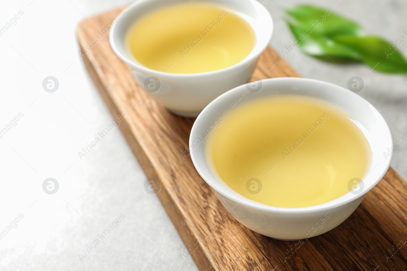 Photo of Stand with cups of freshly brewed oolong tea on table, space for text