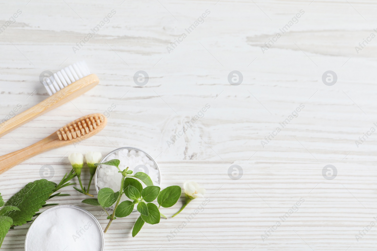 Photo of Flat lay composition with toothbrushes and herbs on white wooden table. Space for text