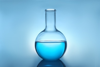 Photo of Flask with liquid on table against color background. Laboratory analysis