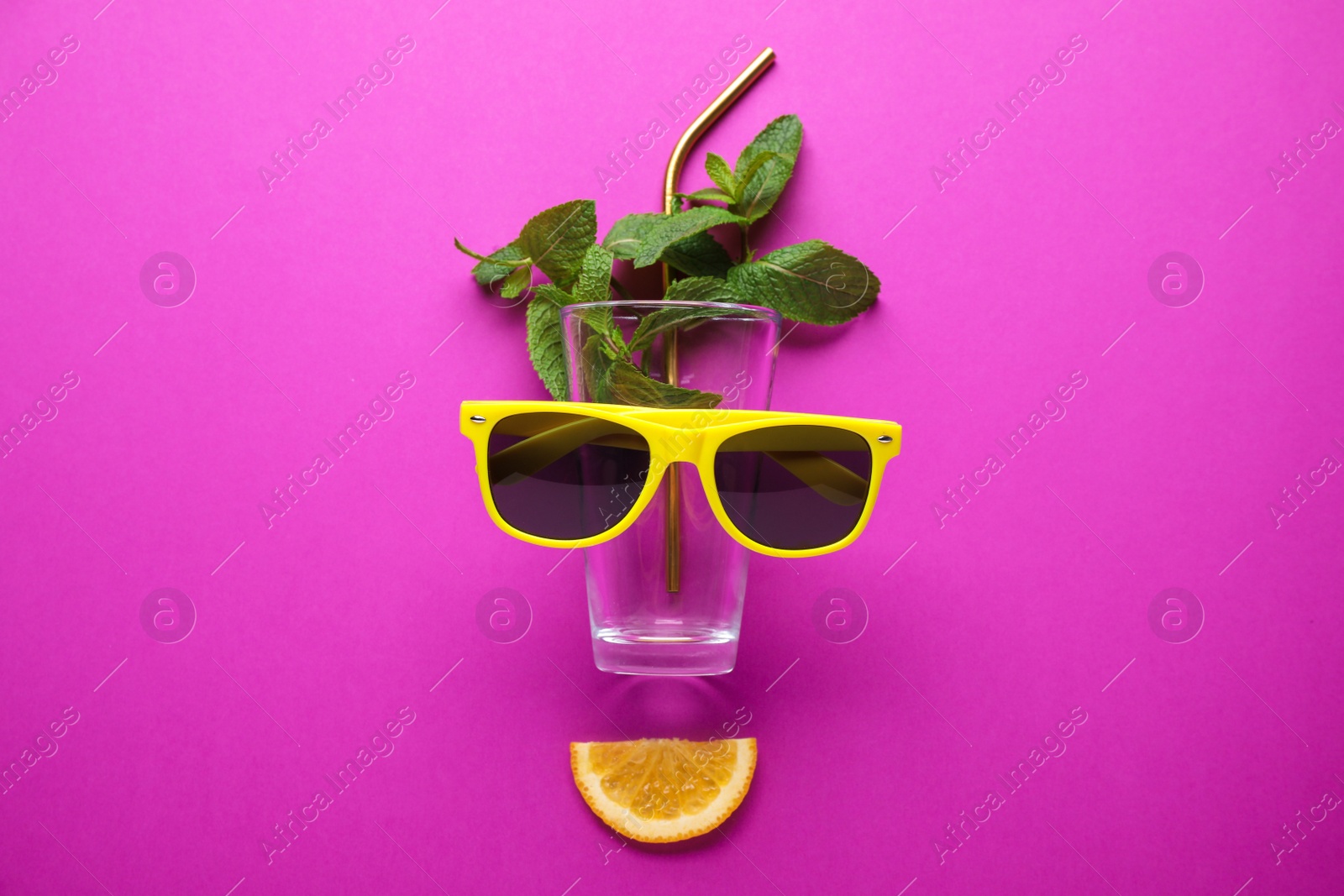 Photo of Creative image of summer cocktail made with mint, glass, sunglasses, citrus slice and straw on color background, flat lay