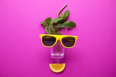 Photo of Creative image of summer cocktail made with mint, glass, sunglasses, citrus slice and straw on color background, flat lay