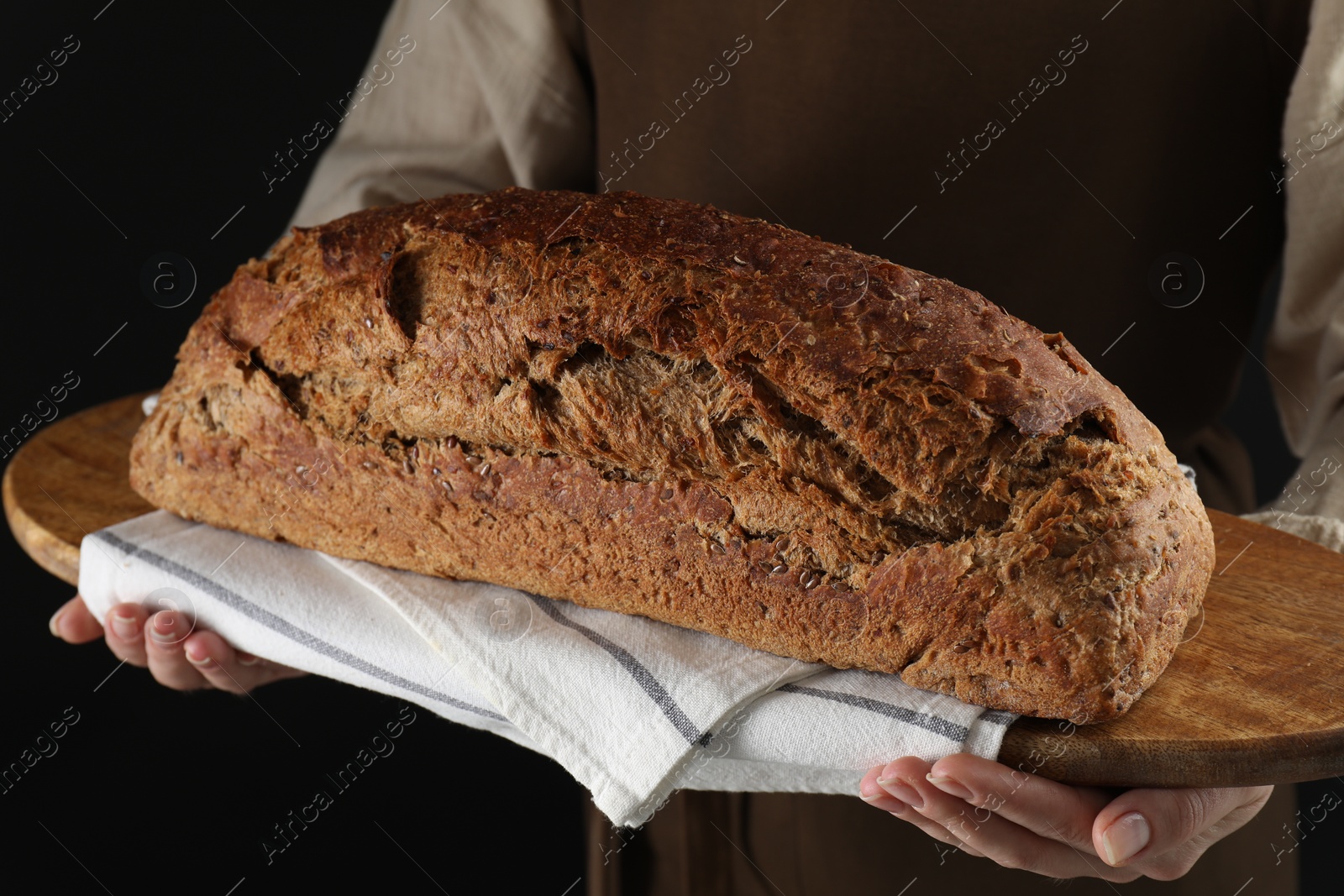 Photo of Woman holding freshly baked bread on black background, closeup