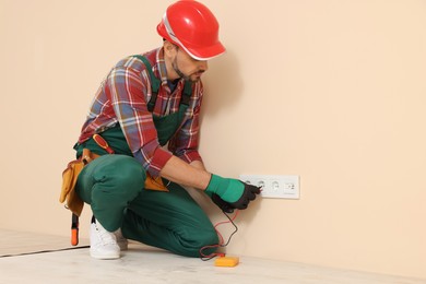 Photo of Electrician in uniform with tester checking voltage indoors