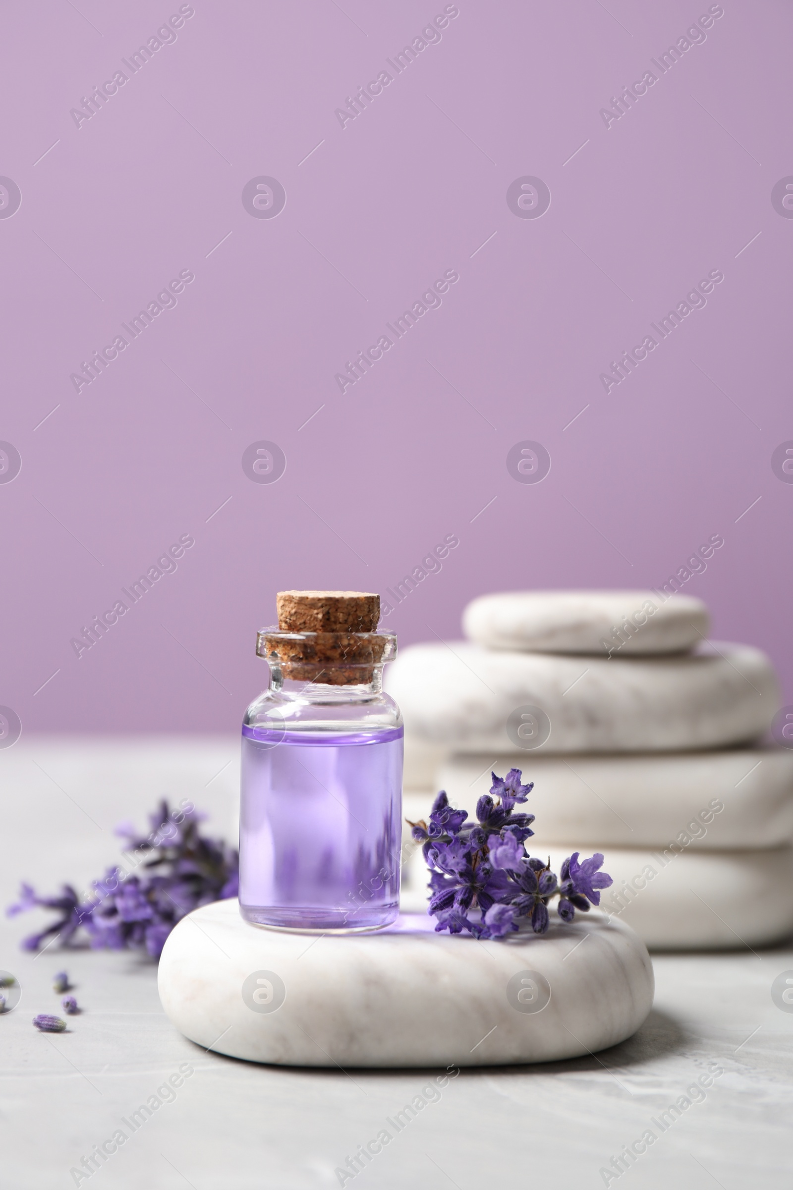 Photo of Stones, bottle of essential oil and lavender flowers on marble table