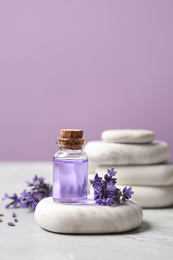 Stones, bottle of essential oil and lavender flowers on marble table