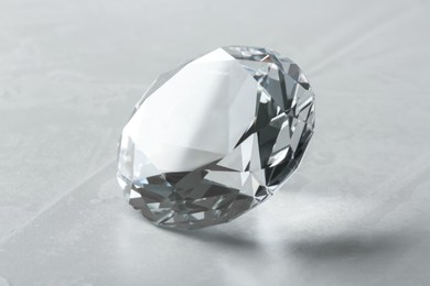Photo of Beautiful shiny diamond on gray table, closeup