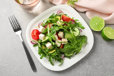 Photo of Delicious salad with feta cheese, arugula and vegetables on grey table, flat lay