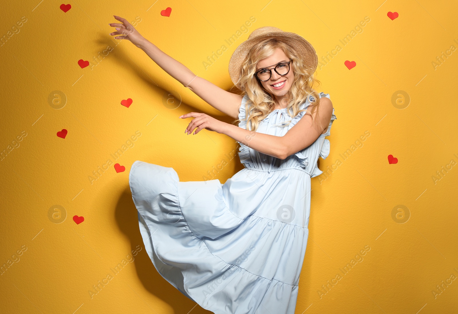 Photo of Stylish young woman with hat and glasses posing on color background