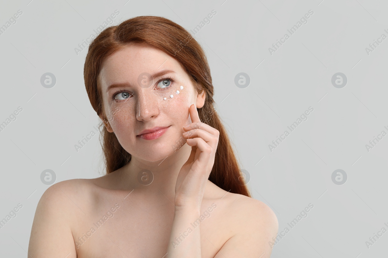 Photo of Beautiful woman with freckles and cream on her face against grey background. Space for text