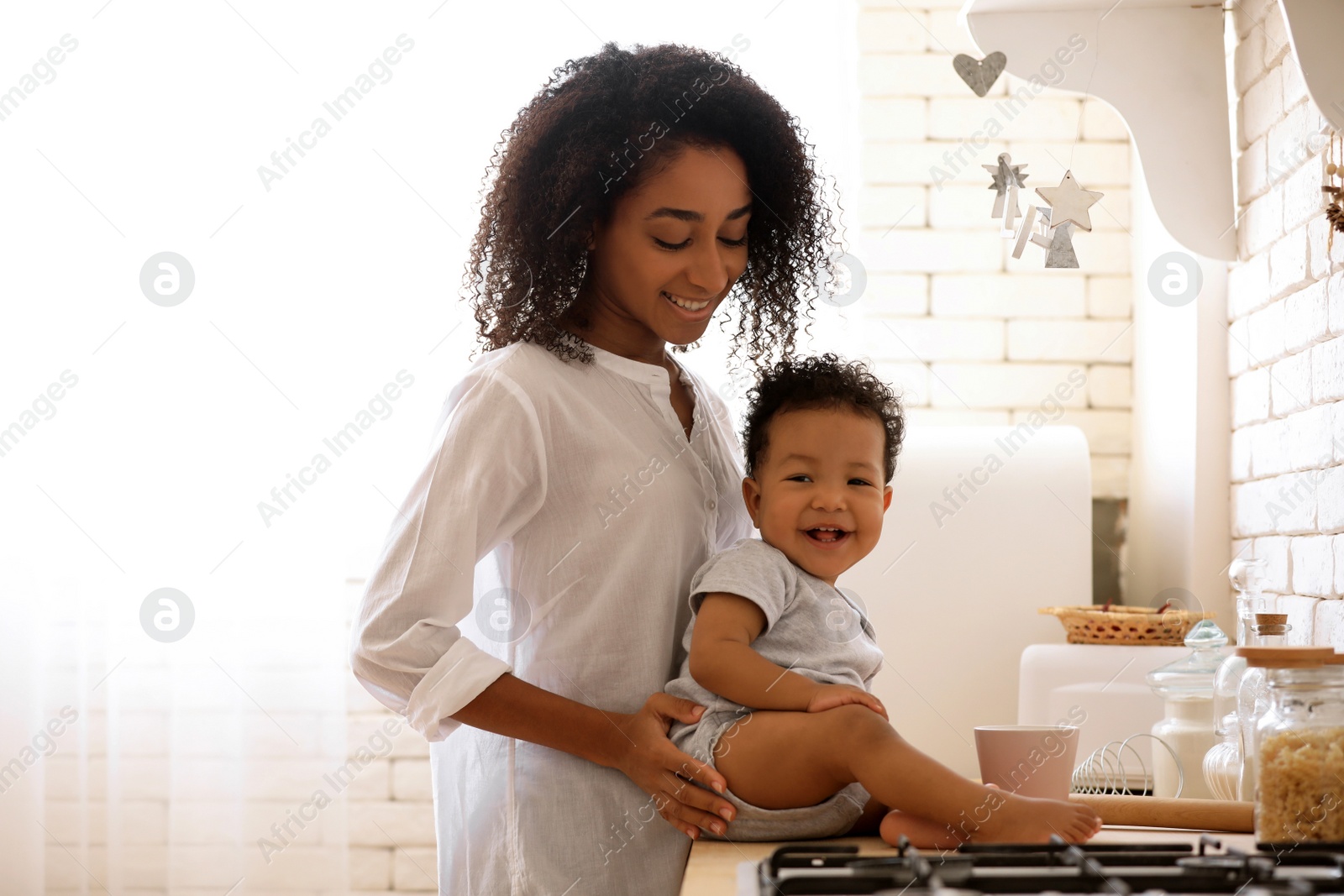 Photo of African-American woman with her baby in kitchen. Happiness of motherhood