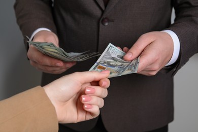 Man giving money to woman on light grey background, closeup. Currency exchange