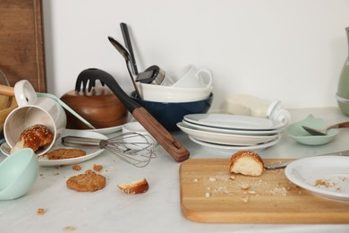 Many dirty utensils, dishware and food leftovers on white countertop. Mess in kitchen