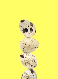 Image of Stacked speckled quail eggs on light yellow background