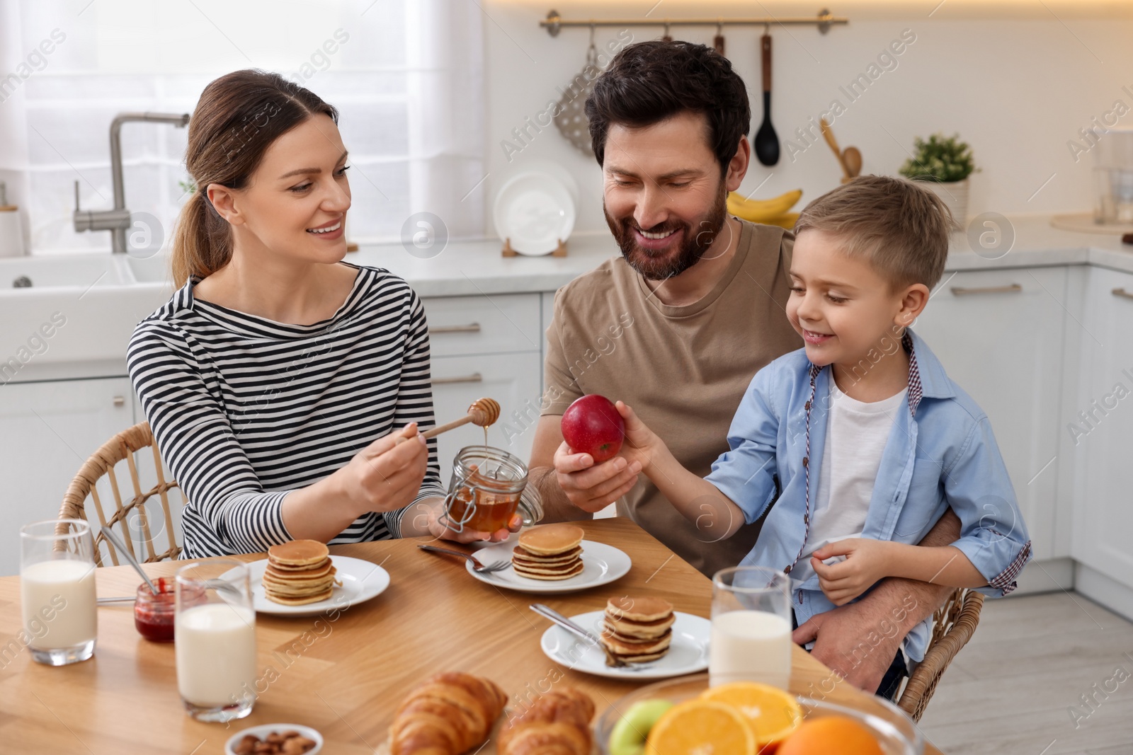 Photo of Happy family having breakfast at table in kitchen