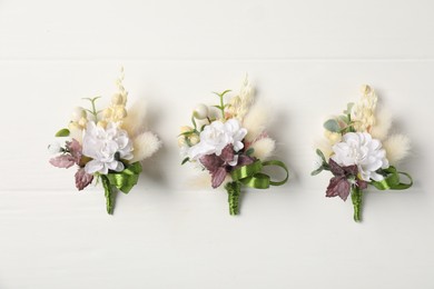 Beautiful boutonnieres on white background, flat lay