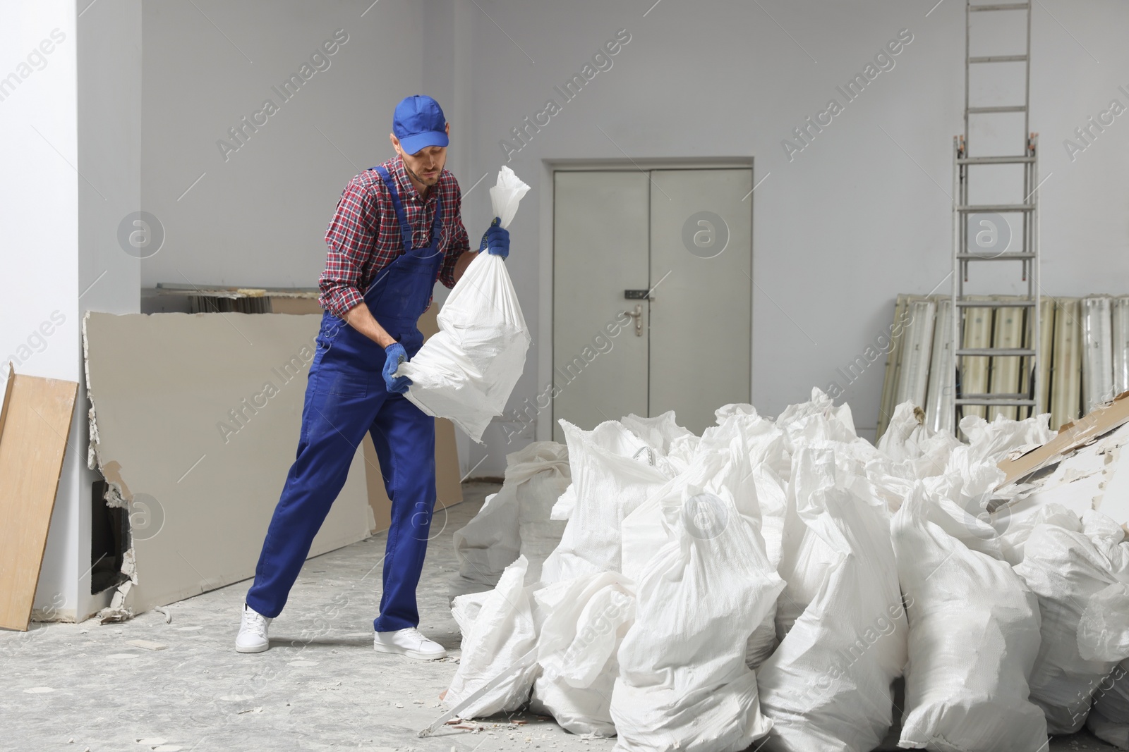 Photo of Construction worker with used building materials in room prepared for renovation