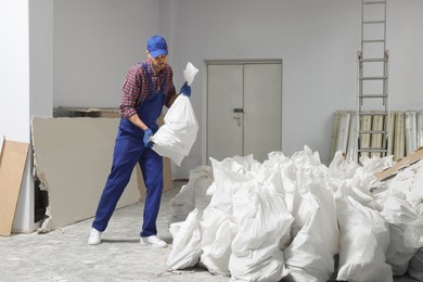 Construction worker with used building materials in room prepared for renovation