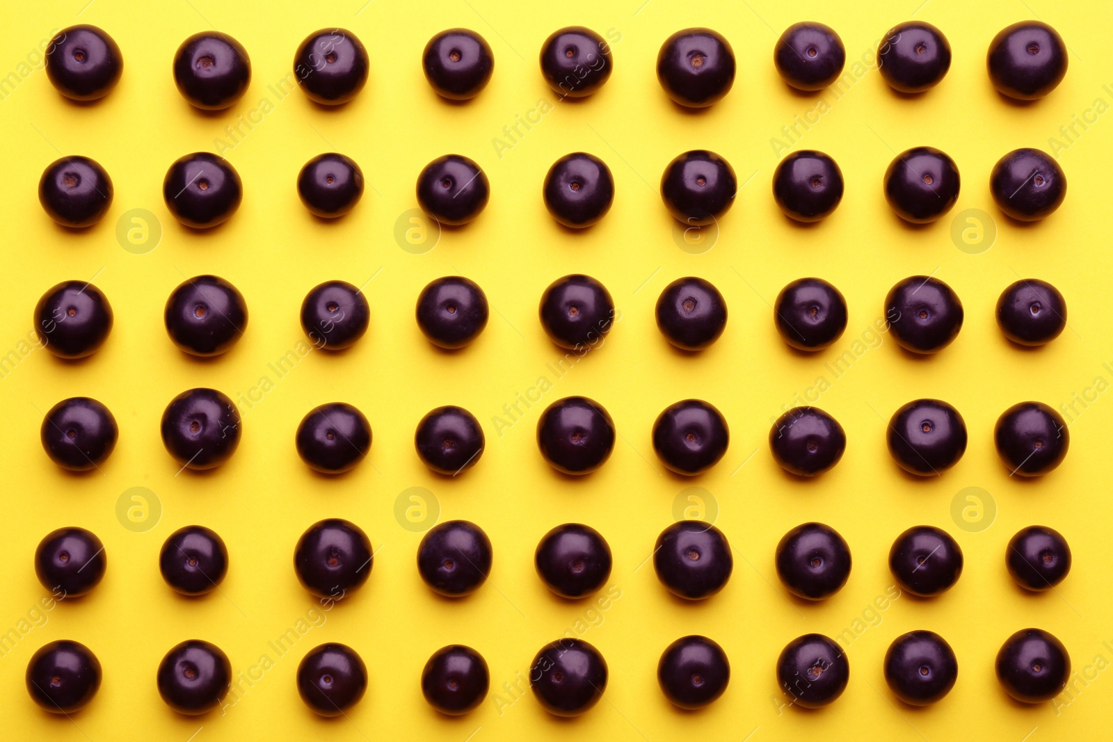 Photo of Fresh acai berries on yellow background, flat lay