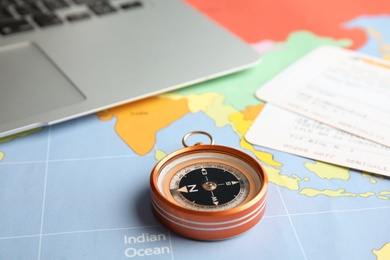 Photo of Compass, tickets and laptop on world map. Travel agency