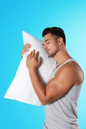 Photo of Young man with soft pillow on color background