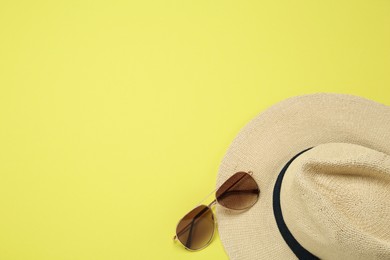 Photo of Hat and sunglasses on yellow background, flat lay with space for text. Sun protection