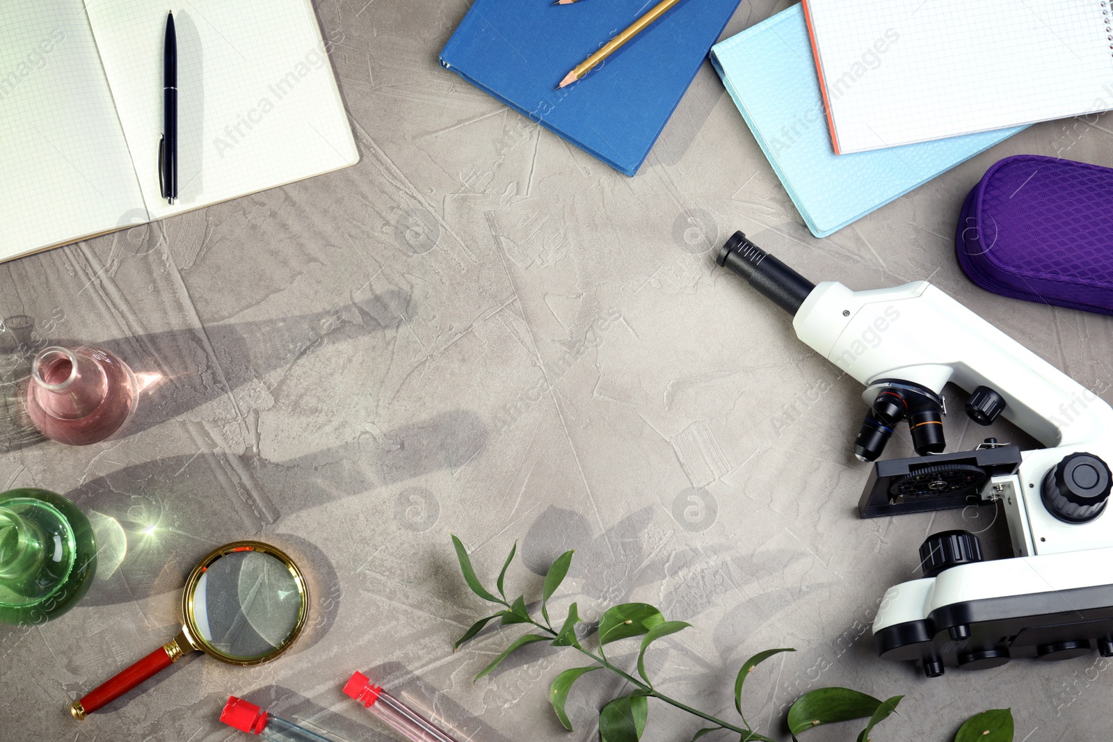 Photo of Flat lay composition with laboratory glassware, microscope and stationery on grey background, space for text. Chemistry concept