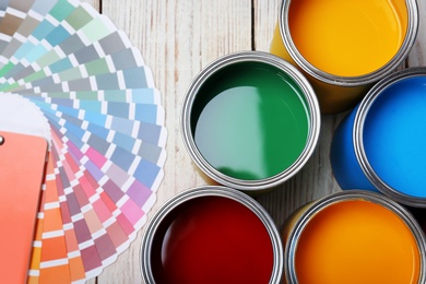 Photo of Cans with paint and color palette on wooden background, top view