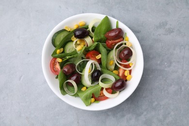 Bowl of tasty salad with leek and olives on grey table, top view