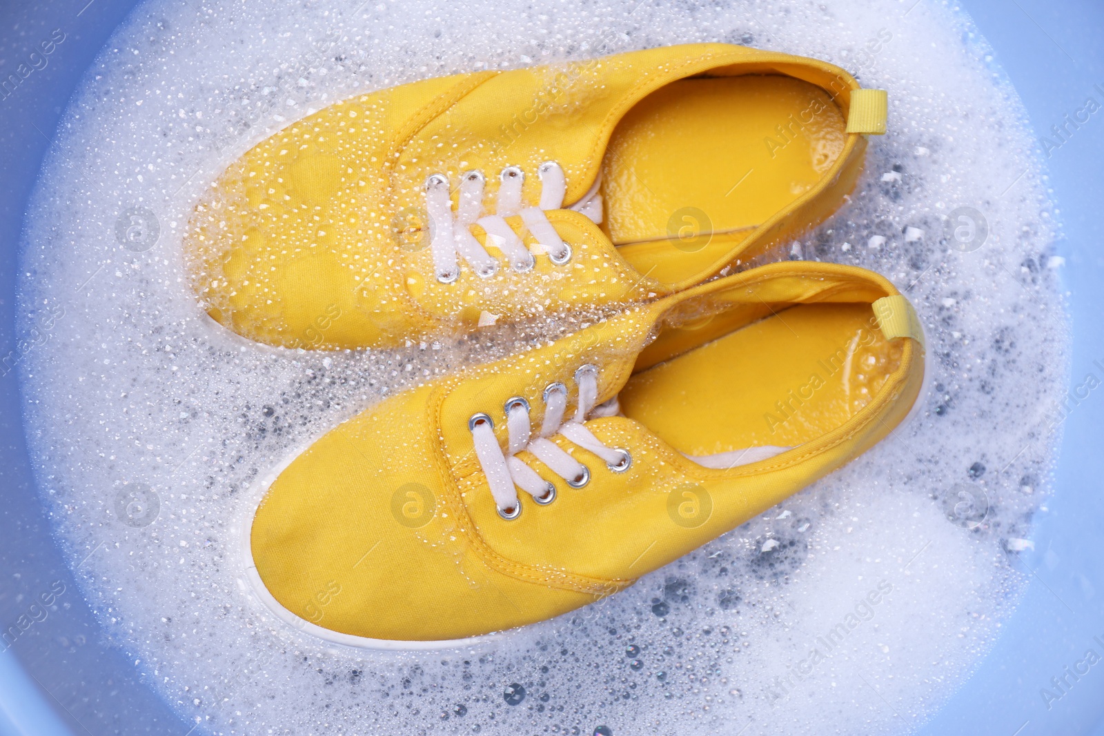 Photo of Washing sport shoes in plastic basin, top view