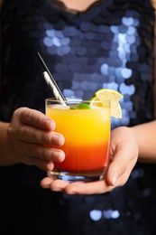 Woman with glass of Tequila Sunrise, closeup. Delicious alcoholic cocktail