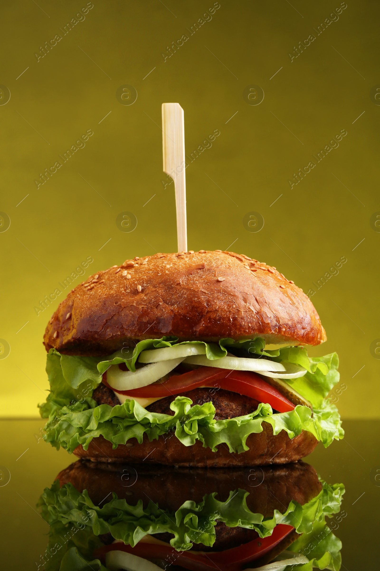 Photo of Delicious vegetarian burger on mirror surface against olive background