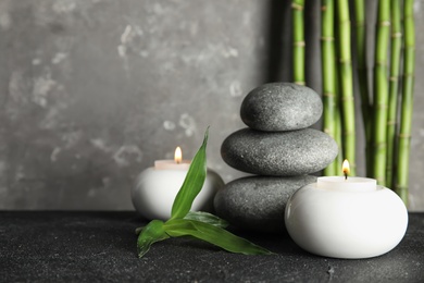 Spa stones with candles and bamboo on table, space for text