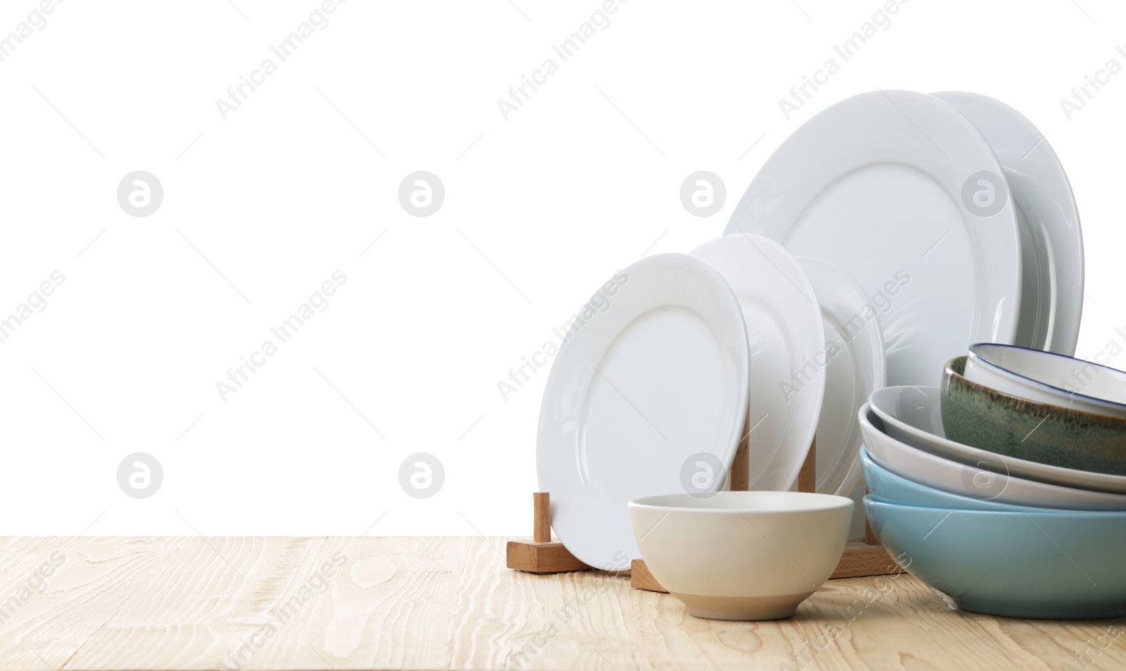 Photo of Set of clean color bowls and plates on wooden table against white background