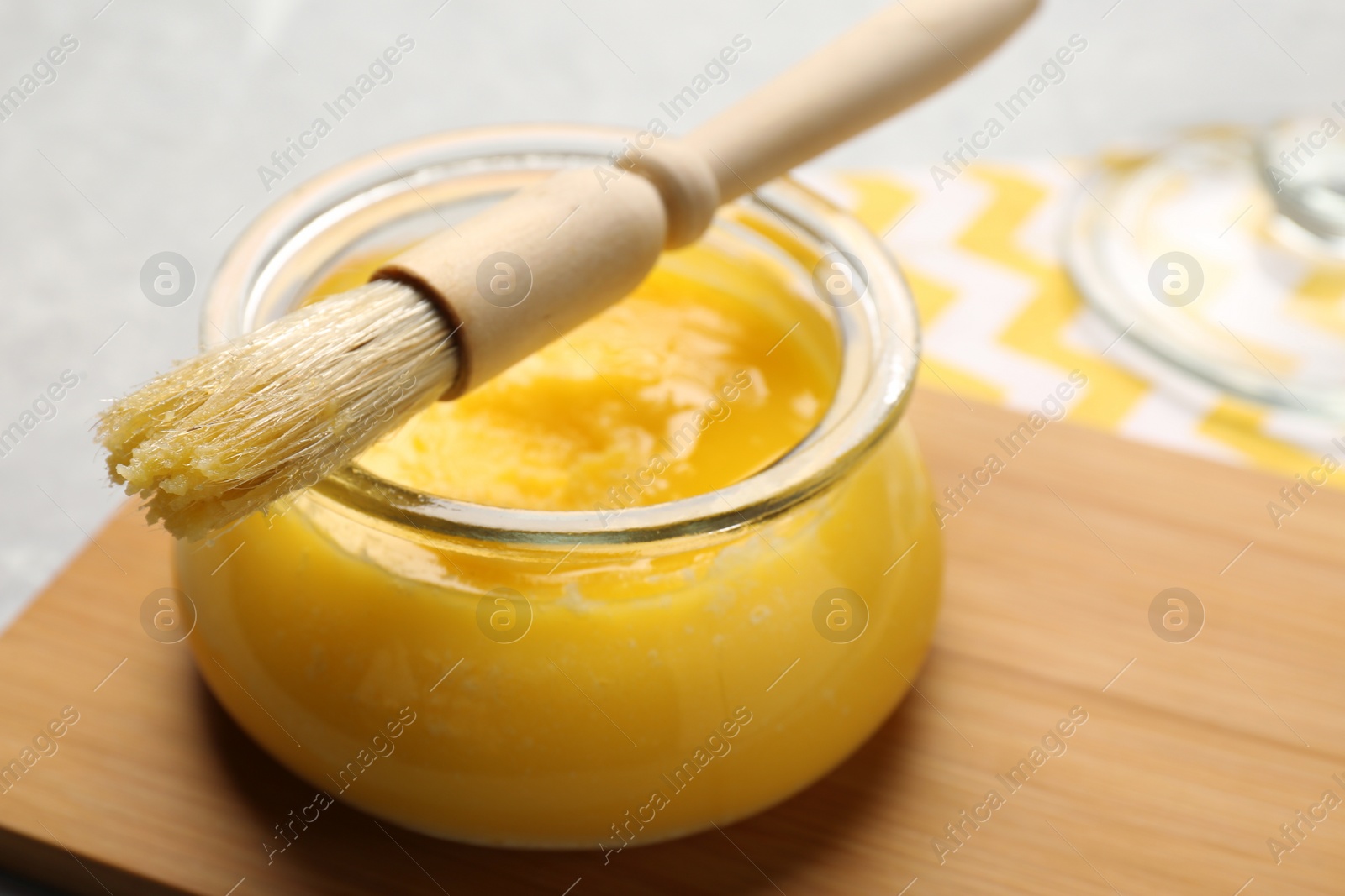 Photo of Wooden board with jar of clarified butter and basting brush on table