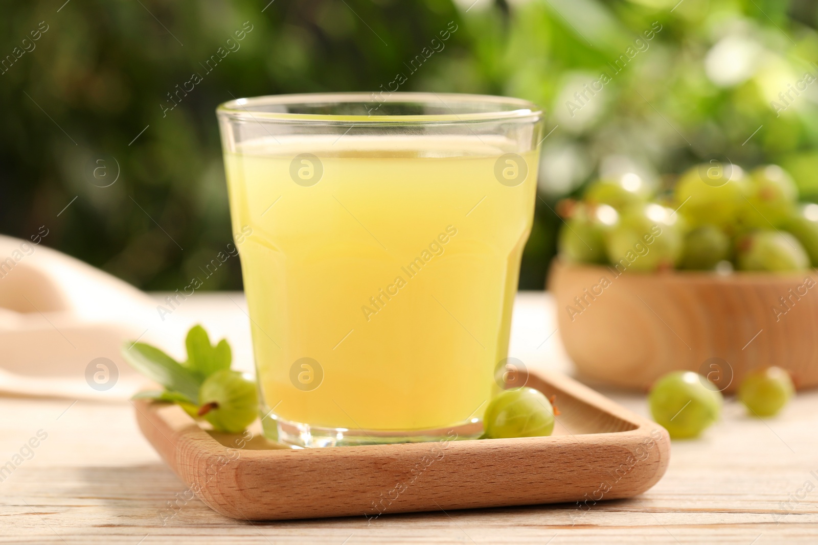 Photo of Tasty gooseberry juice and fresh berries on wooden table