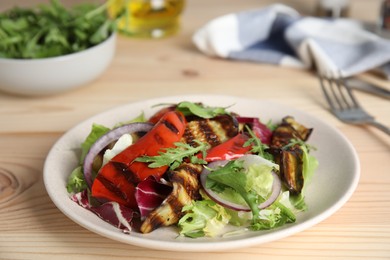 Photo of Delicious salad with roasted eggplant and arugula served on wooden table